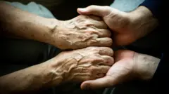 Mãos de pessoa mais velha sendo segurada por mãos mais jovens