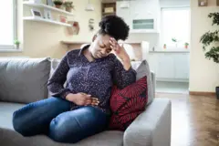 Une femme se tient le ventre sur son canapé