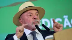 Lula, de terno e gravata e chapéu panamá, discursa com os dedos em riste.