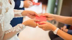 ቀይ ፖስታ የሚሰጥ እጅ