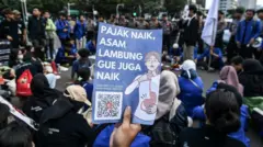 Sejumlah pengunjuk rasa membawa poster saat aksi penolakan PPN 12% di depan Istana Merdeka, Jakarta, Desember 2024.