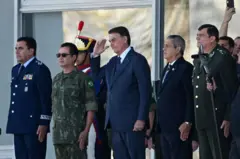 Bolsonaro faz continência durante evento. Ao lado dele há vários militares