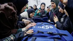 صورة لعدد من النساء يحتشدن حول جثمان شذا الصباغ التي قُتلت أثر اشتباكات في مخيم جنين، ويظهر الجثمان مغطى بسترة زرقاء يرتديها الصحفيون في مناطق النزاعات.