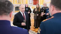 Владимир Путин стоит с бокалом в руках на праздновании в Кремле 