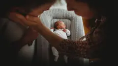 Pais se acariciando com bebê no berço