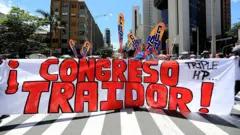 Manifestantes na rua seguram uma faixa que diz "Congresso traidor"