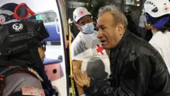 Homem conversa com um paramédico em um edifício derrubado em Los Palos Grandes, Caracas, após os terremotos que sacudiram a Venezuela e outras regiões do Caribe, no dia 24 de junho de 2026