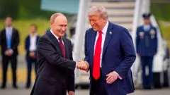 Владимир Путин и Дональд Трамп, улыбаясь, пожимают руки перед трапом самолета