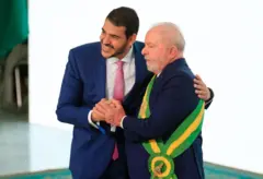 Jorge Messias ao lado de Lula que usa faixa presidencial