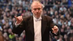  Valery Gergiev leads the London Symphony Orchestra in 2016. Behind him are members of the audience.