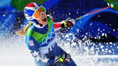 Лыжница радуется успеху, подняв в небо сотни снежных "брызг". На ней форма с олимпийскими кольцами