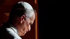 Papa Leão 14 visto de lado, com o os olhos apontados para baixo