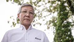Edson Matsui é um senhor vestindo uma camisa branca e óculos de grau.