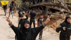 دو زن محجبه با لباس سیاه رنگ، یکی از آنها دستانش را بالا برده وعلامت پیروزی نشان می‌دهد، در پسزمینه ساختمانی ویران و چند کودک دیده می‌شوند