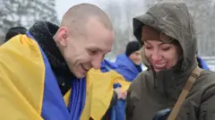 Повернений військовий з українським прапором та працівницею координаційного центру дивляться на екран телефону 