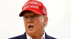 Donald Trump yambaye ingofero itukura yanditseho "make America great again" (cyangwa ongera ugire Amerika igihangange, ugenekereje mu Kinyarwanda)