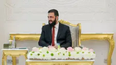 Şara altın varaklı bir koltukta oturuyor 