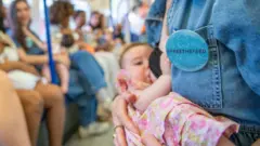 žena drži bebu I doji je u gradskom prevozu 