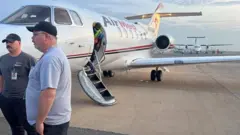 Two men stand beside one aircraft