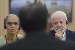Marina Silva e Lula compenetrados durante reunião na COP; eles usam fones de ouvido para tradução