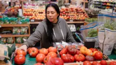 Mulher observa tomates no mercado