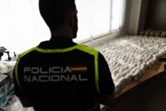 Policial olhando para uma apreensão de droga que está em cima de uma mesa