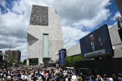 Obama faz seu discurso diante da torre do Centro. Há uma multidão ouvindo e o ex-presidente aparece em um grande telão.