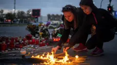 zena i devojcica pale sveće za nastradale ispred zeleznicke stanice u novom sadu