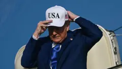 O presidente dos Estados Unidos, Donald Trump, ajusta boné onde se lê "USA" ao sair de avião presidencial que pousou em Amsterdã, para participar da cúpula da OTAN em Haia, em 24 de junho de 2025.
