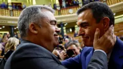 Santos Cerdán, ex-secretário de Organização do partido espanhol PSOE, cumprimenta afetuosamente o primeiro-ministro Pedro Sánchez em plenário