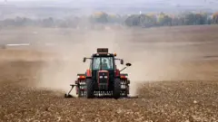 tarlada traktör süren bir çiftçi