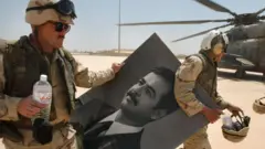 14 अप्रैल 2003 को बगदाद एयरपोर्ट पर अमेरिकी सैनिक सद्दाम के पोर्टेट के साथ