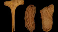 ጥንታዊ ጫማዎቹ አብሮ ከተገኘው የእንጨት መዶሻ ጋር (ከግራ)