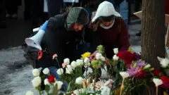 Un hombre y una mujer agachados colocando flores en honor a Renee Nicole Goods, quien falleció a tiros a manos de un agente federal durante una redada migratoria en Mineápolis, Minesota, Estados Unidos, el 7 de enero de 2026. (Foto: David Berding/Getty Images)