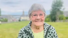 Uma mulher com cabelos grisalhos e usando um óculos