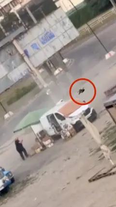 Сабзавот сотувчи киши дронга қараяпти, дрон эса унинг саабзавот сотув машинаси тепасида қизил доира билан кўрсатилган