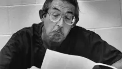 Aldrich Ames em uma fotografia em preto e branco em que aparece lendo um papel