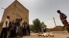أطفال وشباب سودانيون يقفون أمام أنابيب تعرضت للتخريب بسبب الحرب الجارية.