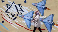 8 Nisan 2026'da Tahran'da bir kadın, ABD ve İsrail karşıtı bir duvar resminin önünden geçerken.
