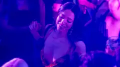 Mikey Madison como Anora, em uma boate