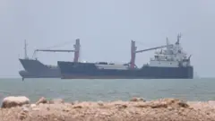 Fotografia colorida mostra dois navios no mar no estreito de Ormuz