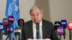 BM Genel Sekreteri Guterres Şam'da basın toplantısında konuşuyor, önünde birçok ajans mikrofonu var - 26 Temmuz