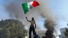 مردی با صورت پوشیده و بدون پیراهن پرچم مکزیک به دست گرفته