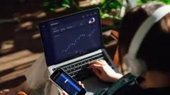 Pessoa olhando suas finanças no computador e no telefone