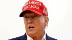 Donald Trump yambaye ingofero itukura yanditseho "make America great again" (cyangwa ongera ugire Amerika igihangange, ugenekereje mu Kinyarwanda) 