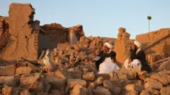 ፍርስራሽ ላይ የተቀመጡ ሰዎች 