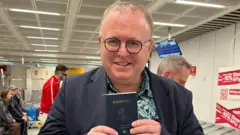 ดร. พอล แชมเบอร์สถือหนังสือเดินทางสหรัฐอเมริกาซึ่งเขาได้รับคืนที่สนามบินสุวรรณภูมิไม่กี่ชั่วโมงก่อนออกจากประเทศไทย