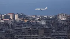 صورة تظهر طائرة تحلق في أفق سماء بيروت حيث تظهر المنازل والبنايات ومن خلفها البحر