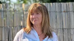 Фото жінки з довгим русявим фарбованим волоссям із чубчиком у світлій блузці