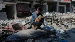 شاب يجلس على صاروخ إسرائيلي مُلقى على الأنقاض في وسط شارع بجوار منازل مُدمرة في مدينة غزة، قطاع غزة، 30 أكتوبر/تشرين الأول 2025، وسط وقف إطلاق نار بين إسرائيل وحماس. 